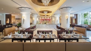 A spacious dining area with multiple tables and booths, a central bar, and a chandelier.