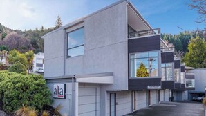 A modern two-story building with a flat roof, large windows, and a sign reading "alta." - Happy Daze Central Queenstown Hot Tub (Queenstown)