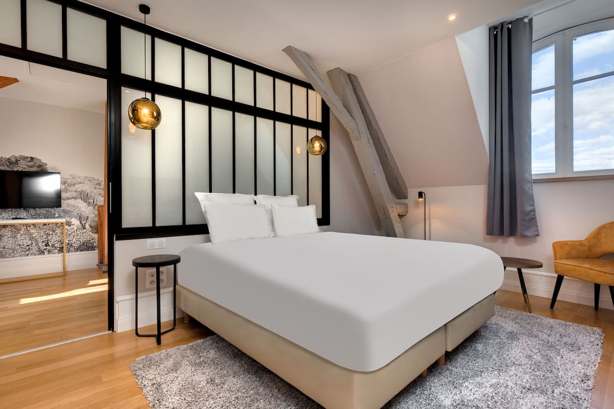 Une chambre moderne avec un grand lit, une télévision, une petite table et une chaise.