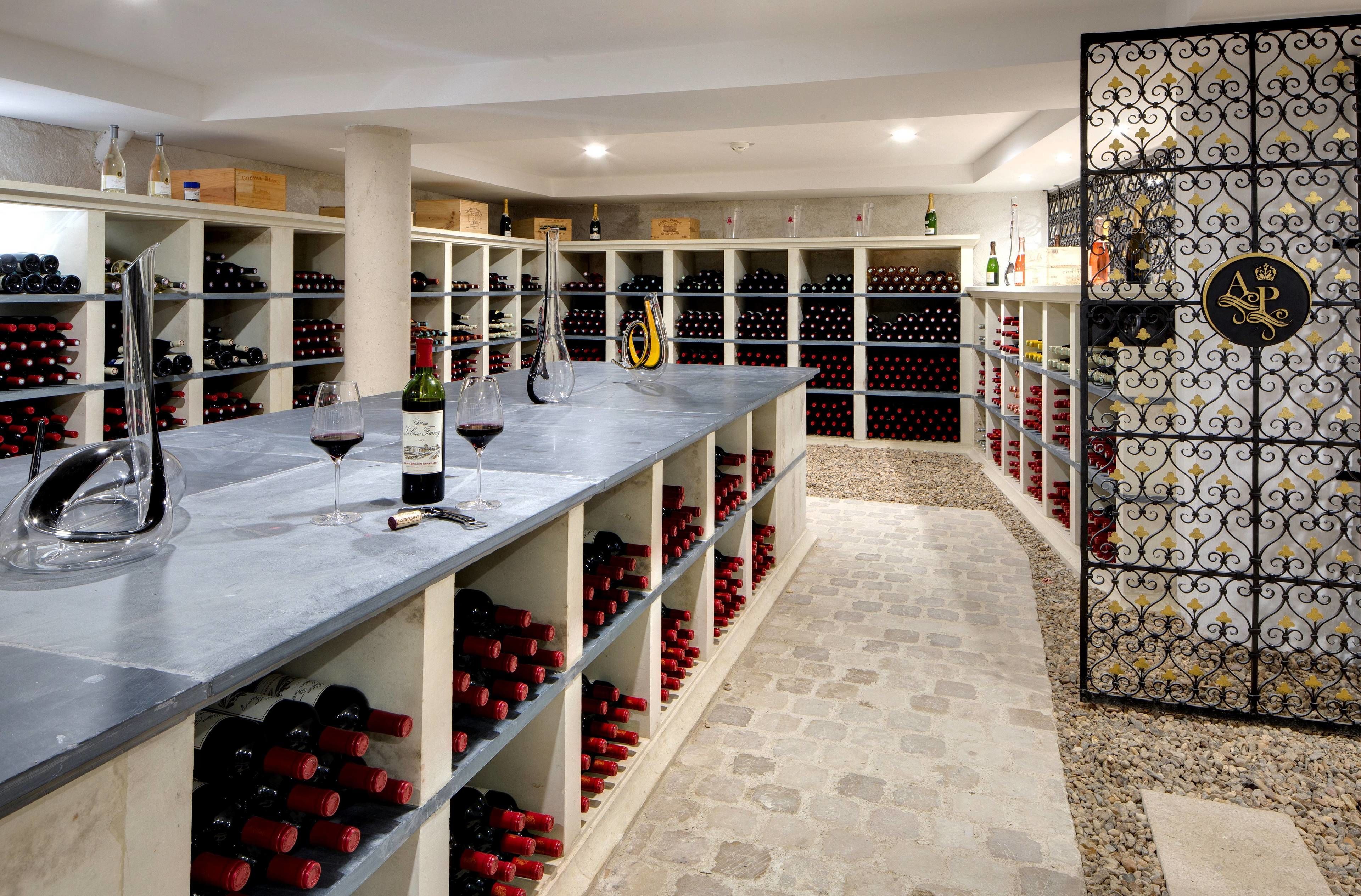 Una bodega con estantes llenos de botellas de vino y una zona de bar con copas y botellas.