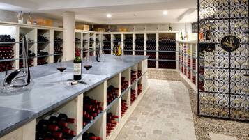 Una bodega con estantes llenos de botellas de vino y una zona de bar con copas y botellas.