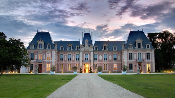 Un grand bâtiment historique à la façade symétrique, doté de nombreuses fenêtres et d’une entrée centrale.
