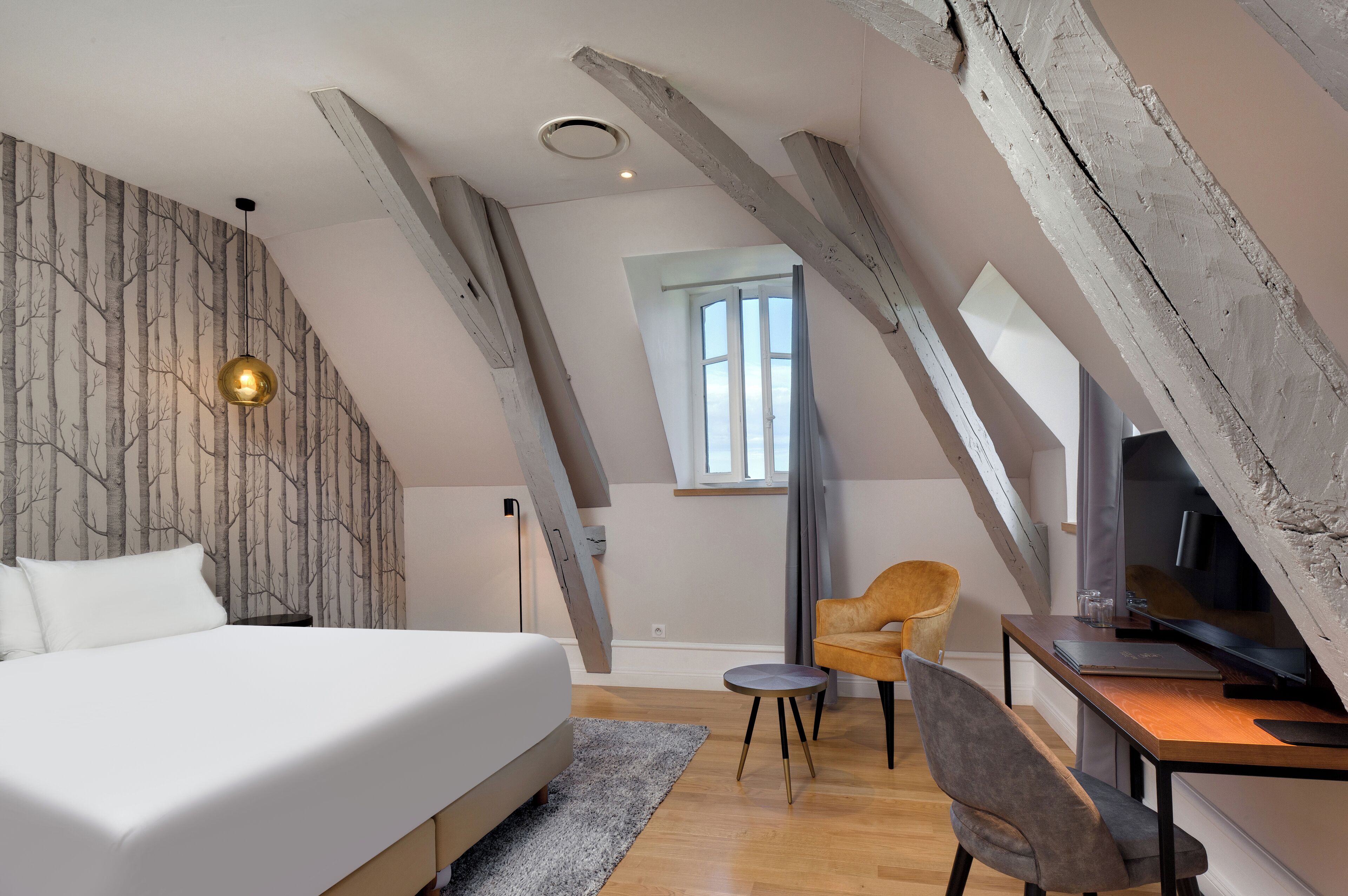A bedroom with a bed, a desk, a chair, and a TV.