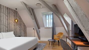 A bedroom with a bed, a desk, a chair, and a TV.
