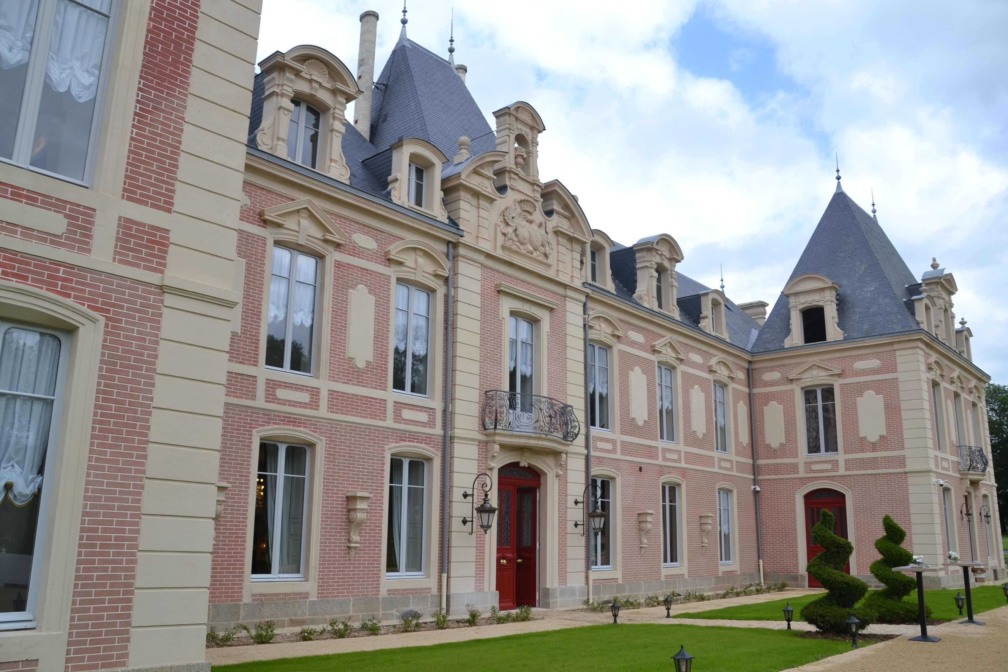 A large, historic building with a symmetrical facade, multiple windows, and a central red door.