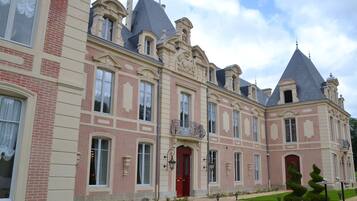 A large, historic building with a symmetrical facade, multiple windows, and a central red door.