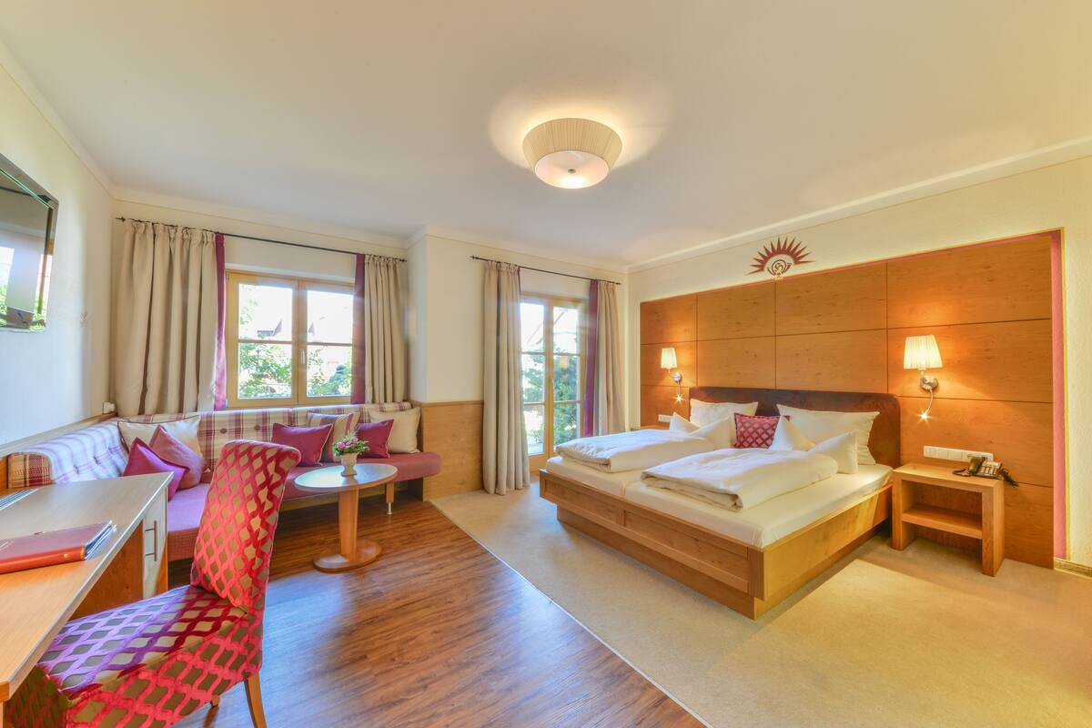 A hotel room with a bed, a sofa, a desk, and a chair.