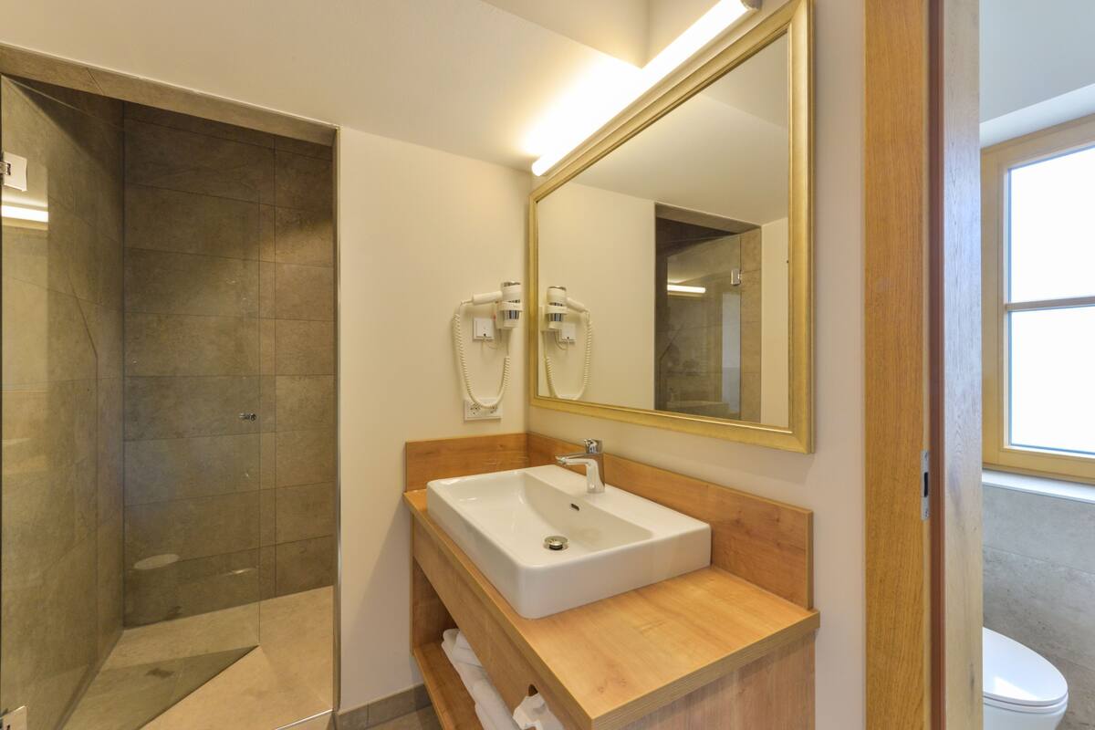 A modern bathroom with a large mirror, a sink, and a shower area.