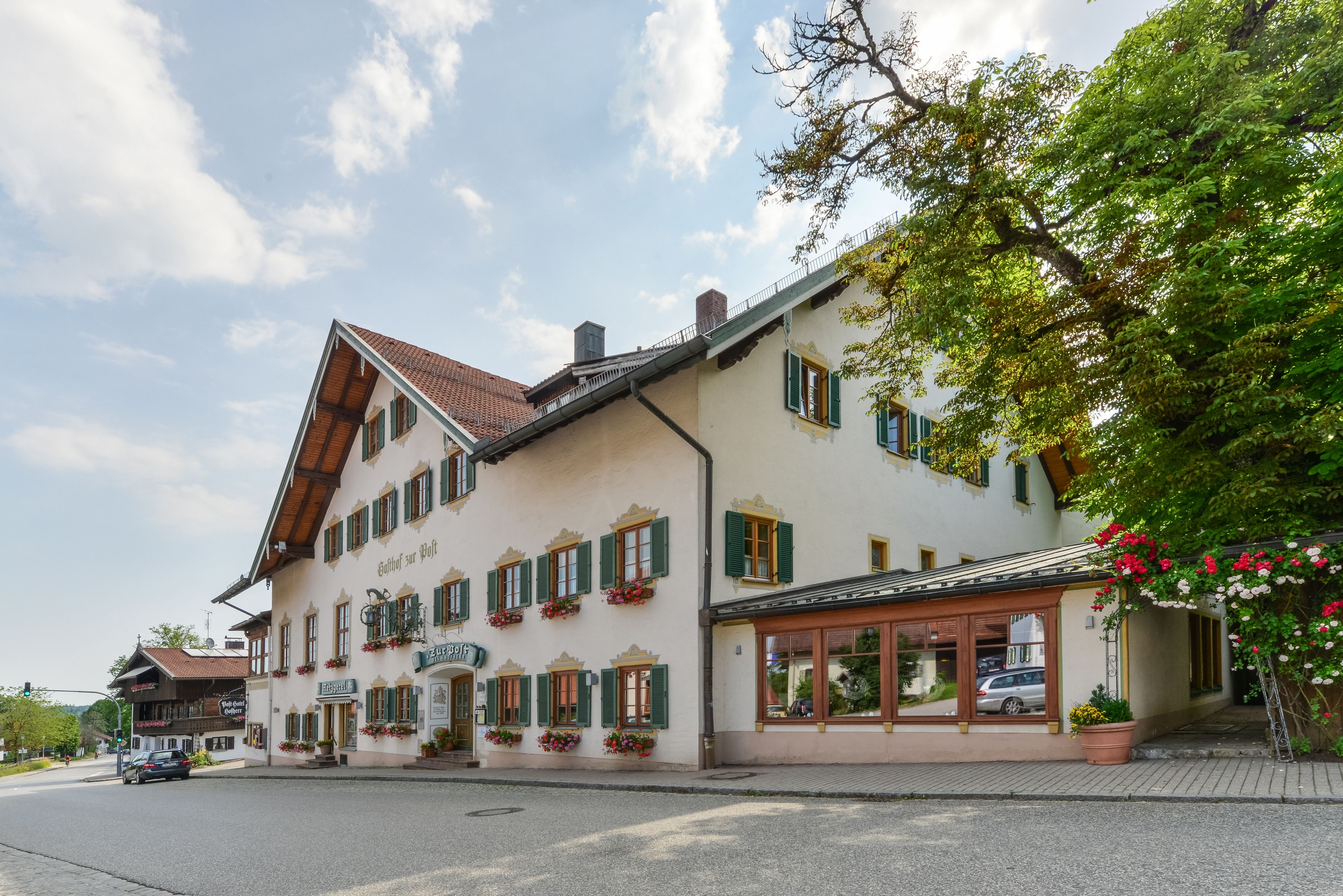 Ein traditionelles europäisches Gebäude mit einem geneigten Dach, zahlreichen Fenstern mit Fensterläden und Blumenkästen an der Fassade.