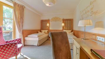 A hotel room with a bed, a desk, a chair, and a window with curtains.