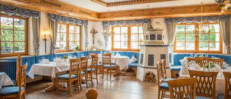 A dining area with wooden furniture, blue upholstered booths, and a central fireplace.