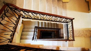Eine Treppe mit Holzgeländer und Metallspindeln, die zu einer Plattform mit einem kleinen, dunkel gefassten Spiegel führt.