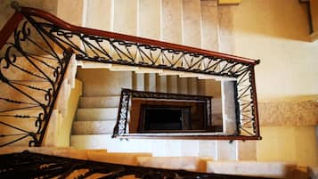 Eine Treppe mit Holzgeländer und Metallspindeln, die zu einer Plattform mit einem kleinen, dunkel gefassten Spiegel führt.