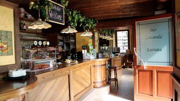 Eine Bar mit Holztresen, einer Kreidetafel und hängenden Pflanzen.