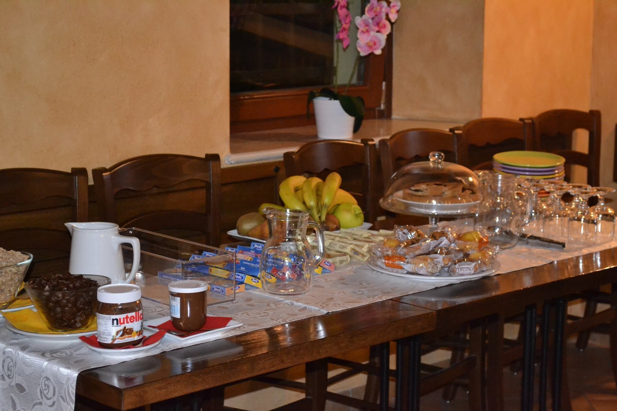 A dining table set with various food items, including fruits, condiments, and a pitcher.