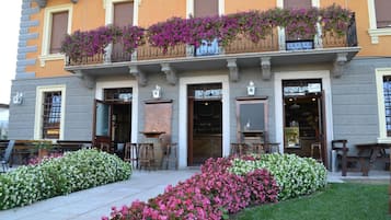 Ein Gebäude mit einem Balkon, der mit violetten Blumen geschmückt ist, einer Steinfassade und Außenplätzen.