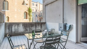 A balcony with a table and chairs, a green bottle, a kettle, and a blue bag. - Venezia - Lido Erizzo 15 (Venice)