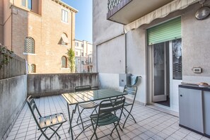 A balcony with a table and chairs, a sliding door, and a view of neighboring buildings. - Venezia - Lido Erizzo 15 (Venice)