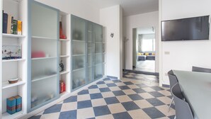 A modern living room with a checkered floor, a flat-screen TV mounted on the wall, and a sliding glass door closet. - Venezia - Lido Erizzo 15 (Venice)
