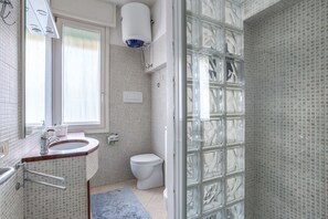 A bathroom with a white sink, a toilet, and a glass shower enclosure. - Venezia - Lido Erizzo 15 (Venice)