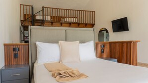 A bedroom with a bunk bed, a single bed, a TV mounted on the wall, and a wooden headboard. - Hotel Checkin El Cortecito Beach (Punta Cana)