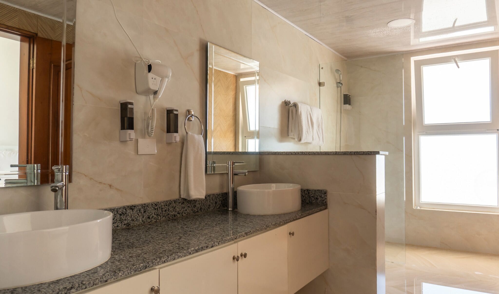 Ein modernes Badezimmer mit einem großen weißen Waschbecken, einer Granit-Arbeitsplatte, einem Spiegel und einem Handtuchhalter.