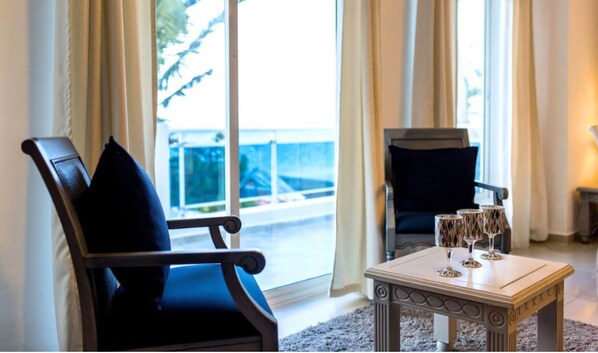 A room with a large window, a wooden table with two glasses, and two chairs.
