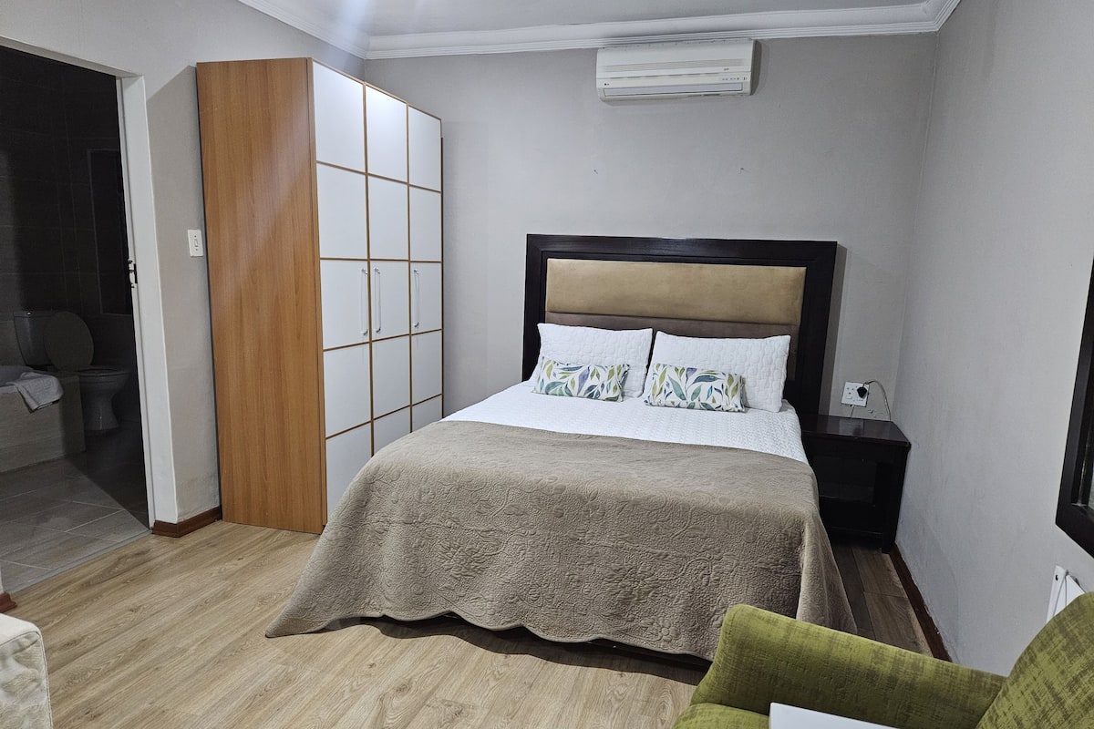 Une chambre à coucher avec un lit, une armoire, une table de chevet et une fenêtre.