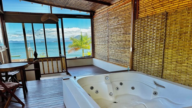 Ein Zimmer mit großem Fenster, einer Holzterrasse und einem Whirlpool.