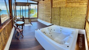 Ein Balkon mit Whirlpool, Holzboden und einem Tisch mit Stühlen.
