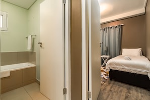 A hotel room with a bathroom, a bed, and a small table.