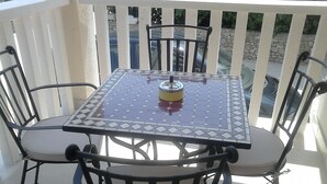 A square table with a patterned tabletop and four chairs with armrests. - Apartments Juliet (Orebic)