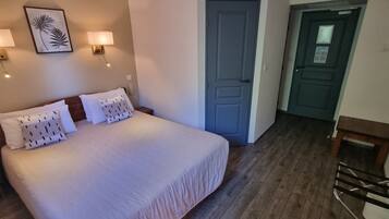 Une chambre à coucher avec un lit, deux lampes fixées au mur, une porte et une chaise en bois.