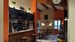 A cozy bar area with a wooden counter, stools, and a chalkboard menu. - Le Pradet Hotel (Vacqueyras)
