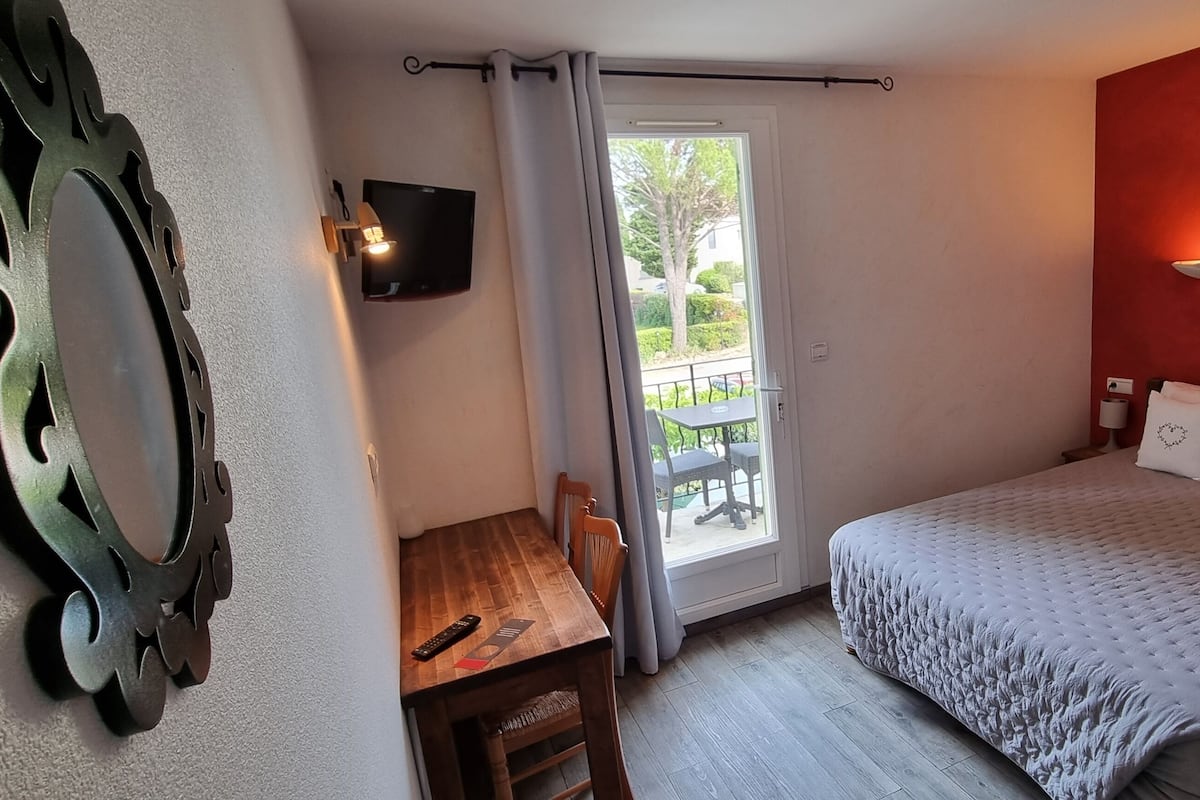 A bedroom with a bed, a desk, a TV, and a balcony.