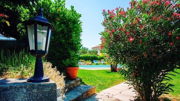 A stone pathway leading to a house with a potted plant and a lantern. - Le Pradet Hotel (Vacqueyras)