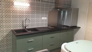 Eine Küche mit Spüle, Schränken und einem Essbereich mit Tisch und Stühlen.