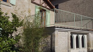 Ein Gebäude mit Balkon, Steinmauer und Fenster mit grünem Rollo.