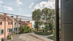 A view from a balcony overlooking a courtyard with trees and a body of water. - Venezia - Castello 1542 (Venice)