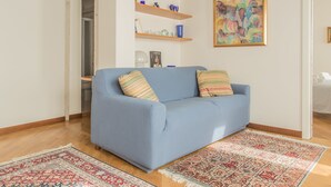 A living room with a blue sofa, wooden beams on the ceiling, a colorful painting, and a patterned rug. - Venezia - Castello 1542 (Venice)