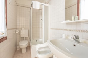 A bathroom with a toilet, bidet, shower, and sink.