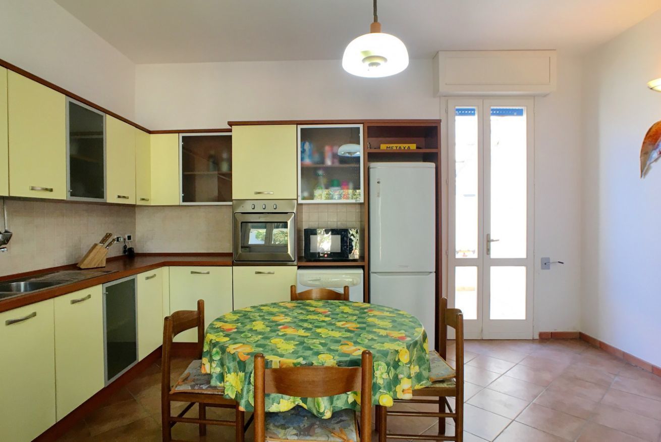A compact kitchen with a dining table, chairs, a microwave, oven, and a refrigerator.