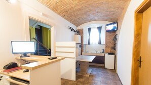 A compact kitchen with a computer desk, a microwave, and a refrigerator.