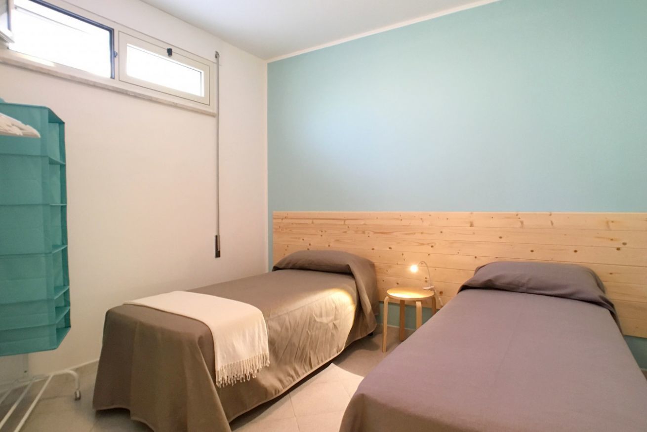 Une chambre avec deux lits, une petite table et une fenêtre.