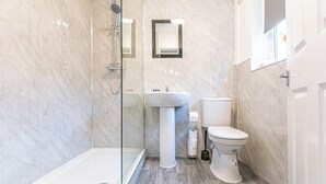 Ein modernes Badezimmer mit Duschkabine aus Glas, einem Standwaschbecken und einer Toilette.