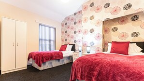 A hotel room with two beds, a wardrobe, a desk, and a window with blinds. - Comfy 3-Bedroom House – Great for NHS, Contractors & Long Stays (St Helens)