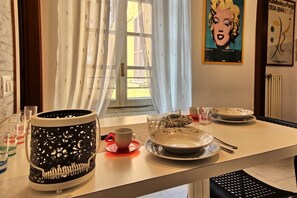 A dining area with a table set for two, featuring a black and white patterned vase, a red cup, and a plate with a floral design. - Antica Corte Bonanomi (Como)