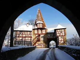 Um edifício histórico com uma torre imponente e uma entrada coberta de neve sob um arco.