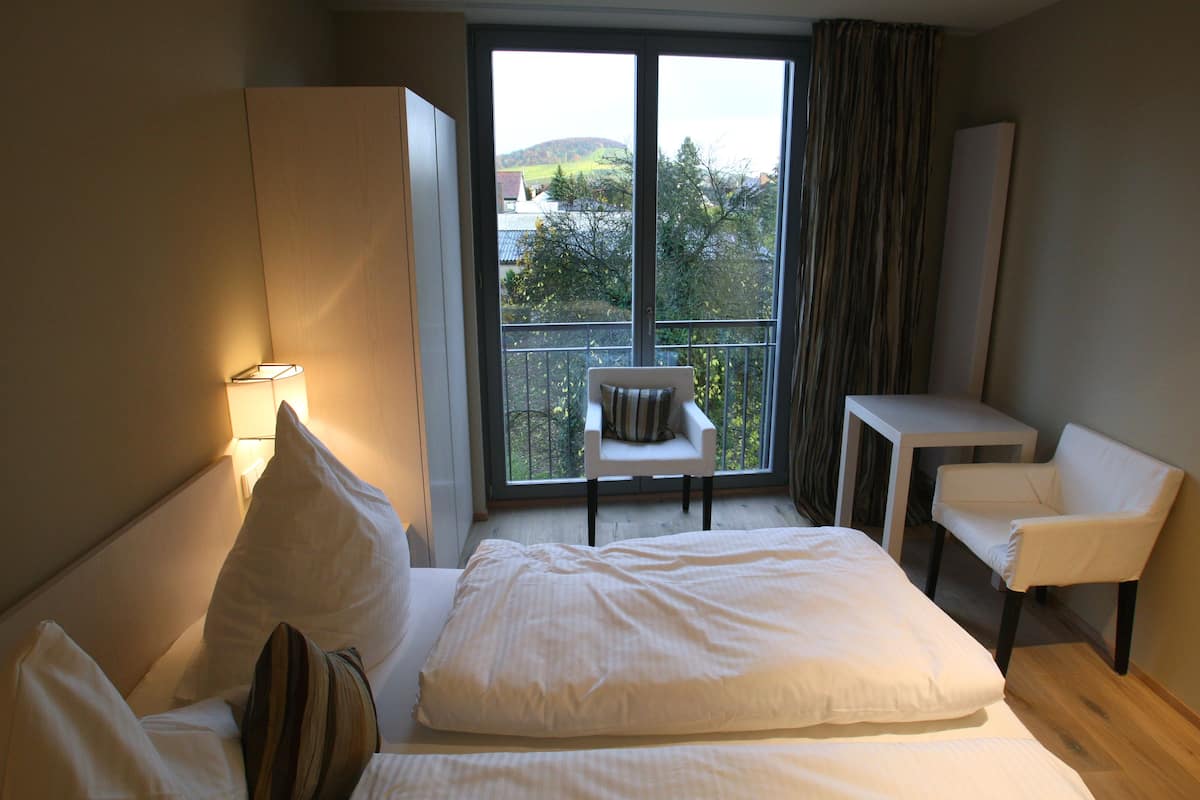 Une chambre d’hôtel avec un lit, une chaise, une petite table et une vue sur l’extérieur.