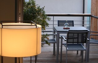 Um pátio externo com mesa, cadeiras, um abajur e uma cúpula de vidro decorativa.